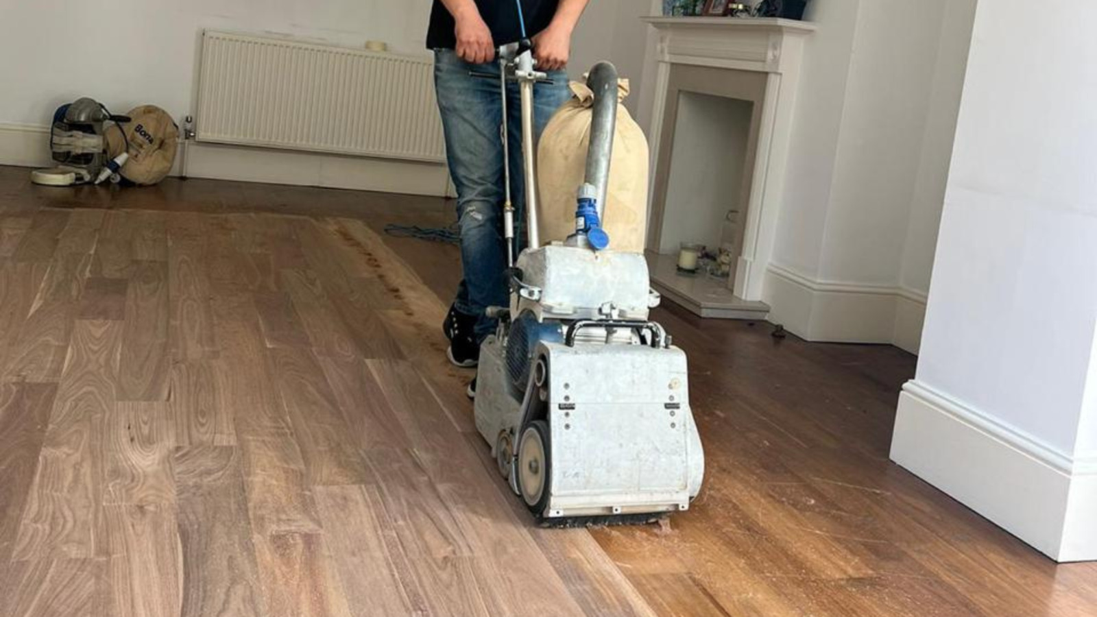 A Man from https://floor-sanding-kent.org/ Sanding a hardwood floor in a home in KENT, UK