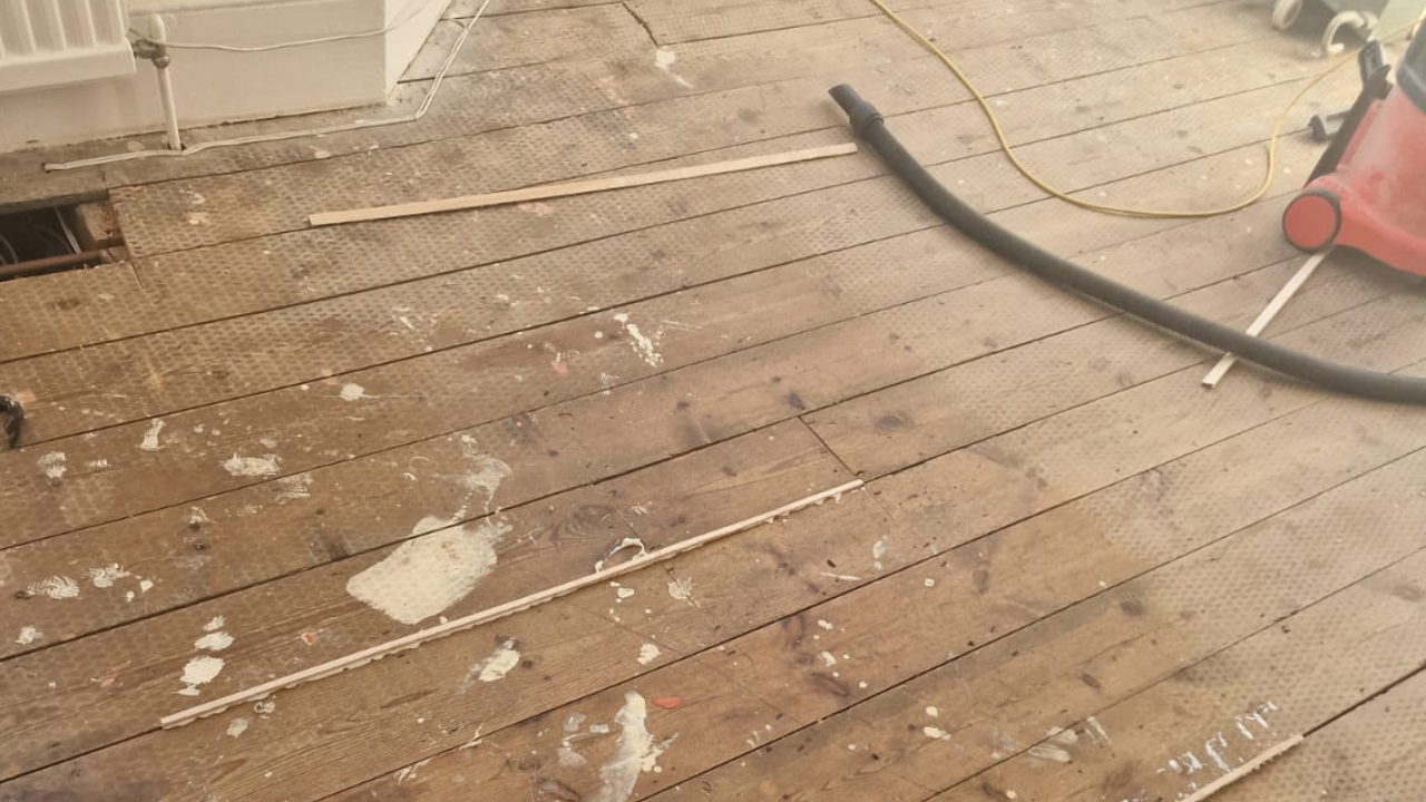 Close-up of a paint-stained, worn wooden floor in Kent before professional Wood Floor Sanding in Kent.