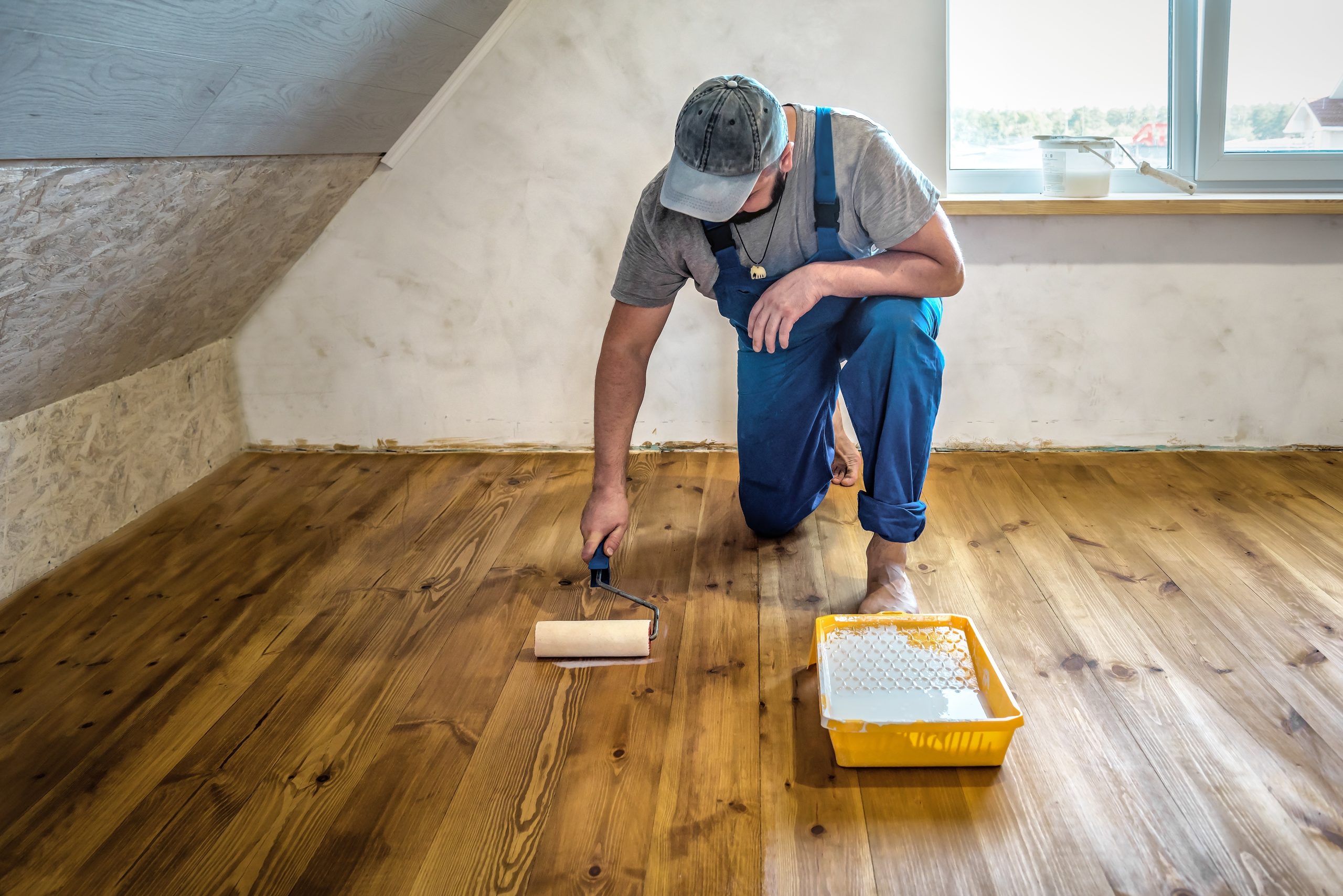 A professional applying a finish coat to a sanded wooden floor, illustrating the final stage of Wood Floor Sanding in Kent.