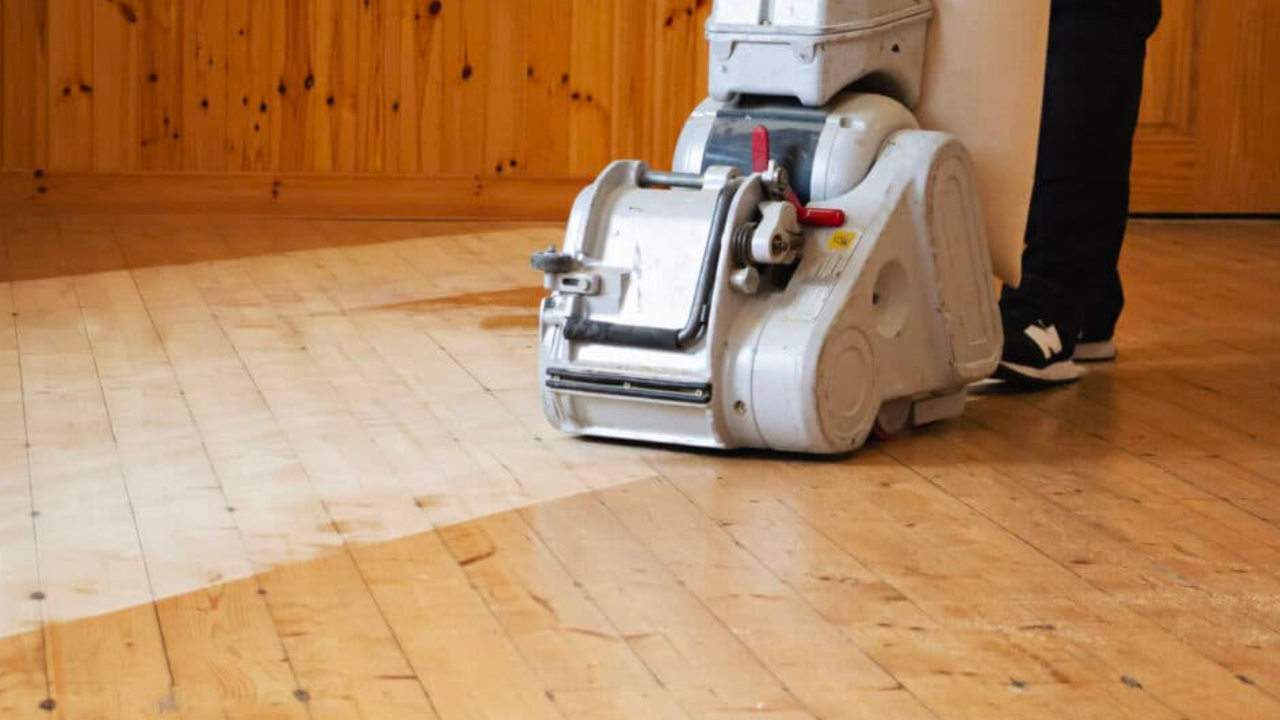 A professional floor sanding machine in use, revealing the contrast between the unfinished and newly sanded sections during Wood Floor Sanding in Kent.
