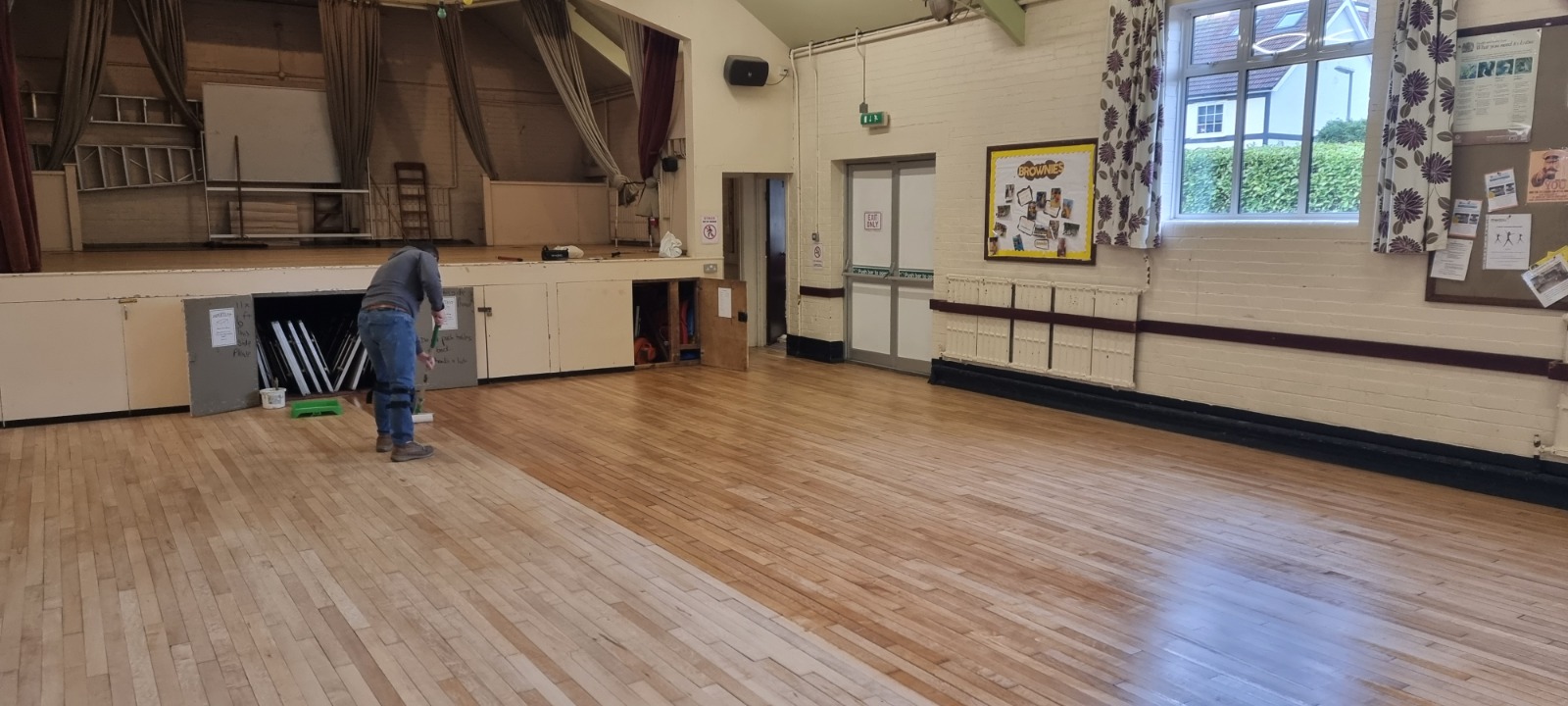 Commercial Floor Sanding in Kent – contractor applying lacquer to a newly sanded maple strip hardwood hall floor during refurbishment.