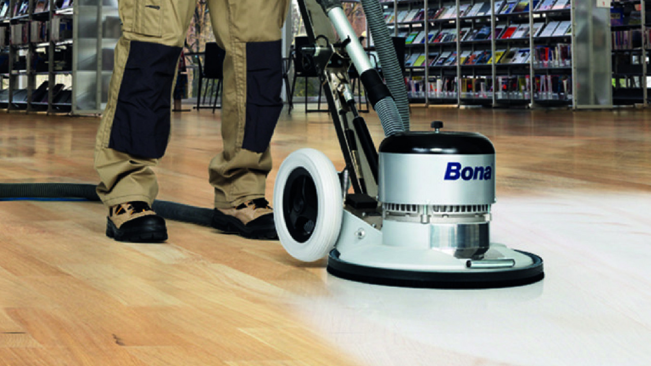 Commercial Floor Sanding in Kent – technician using a Bona rotary machine to screen and refine an oak hardwood plank floor in a commercial building.