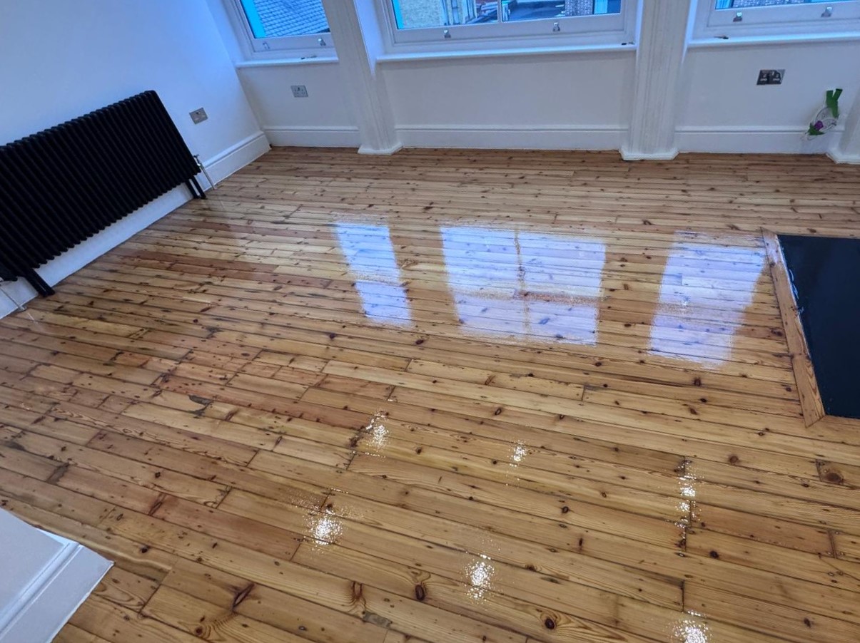 Wood Floor Sanding in Kent on natural solid pine floorboards, showing a large living room with a high-gloss restored timber finish.
