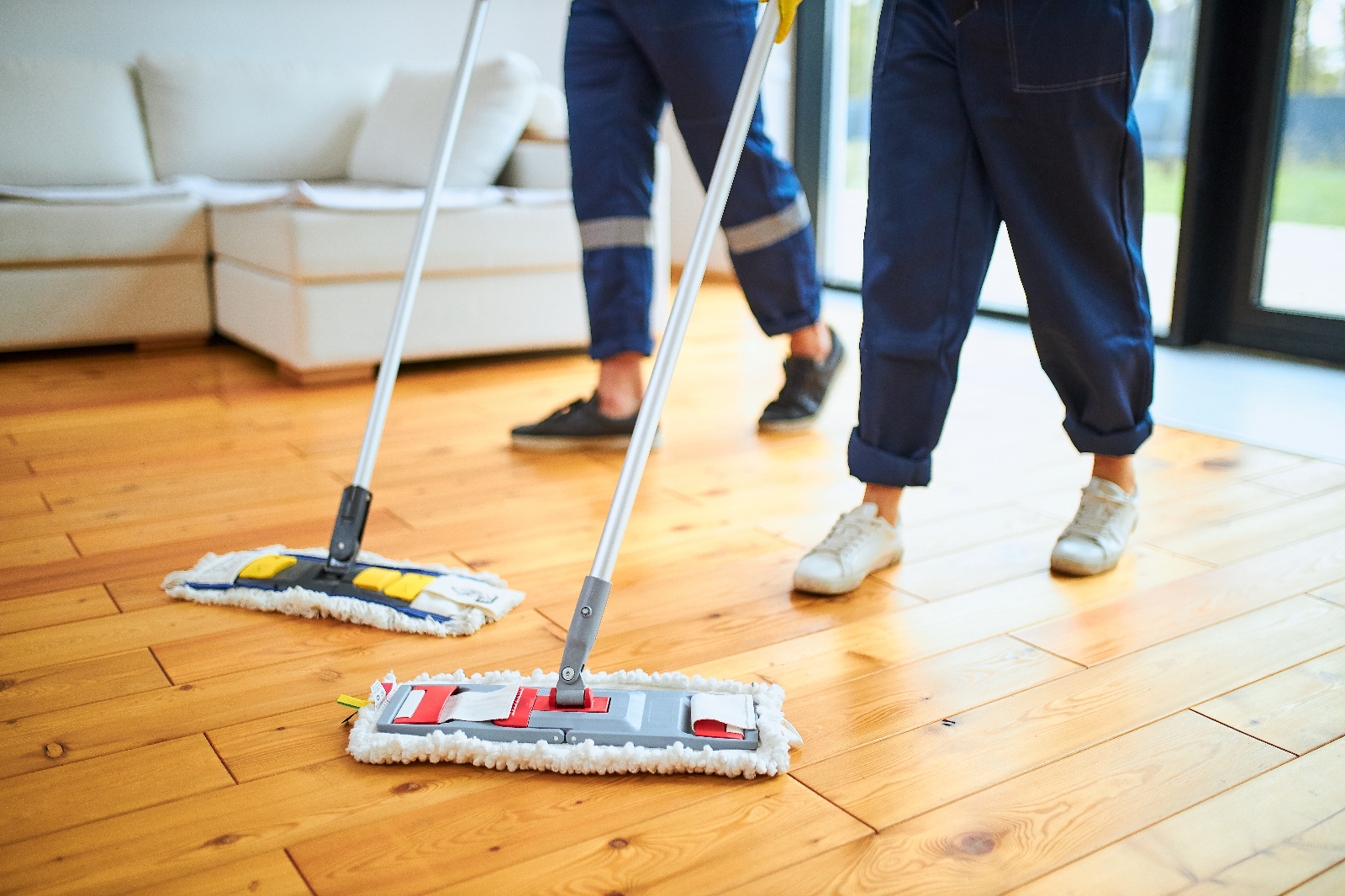 Wood Floor Sanding in Kent with two professionals cleaning a restored solid pine softwood plank floor in a modern living room after sanding.